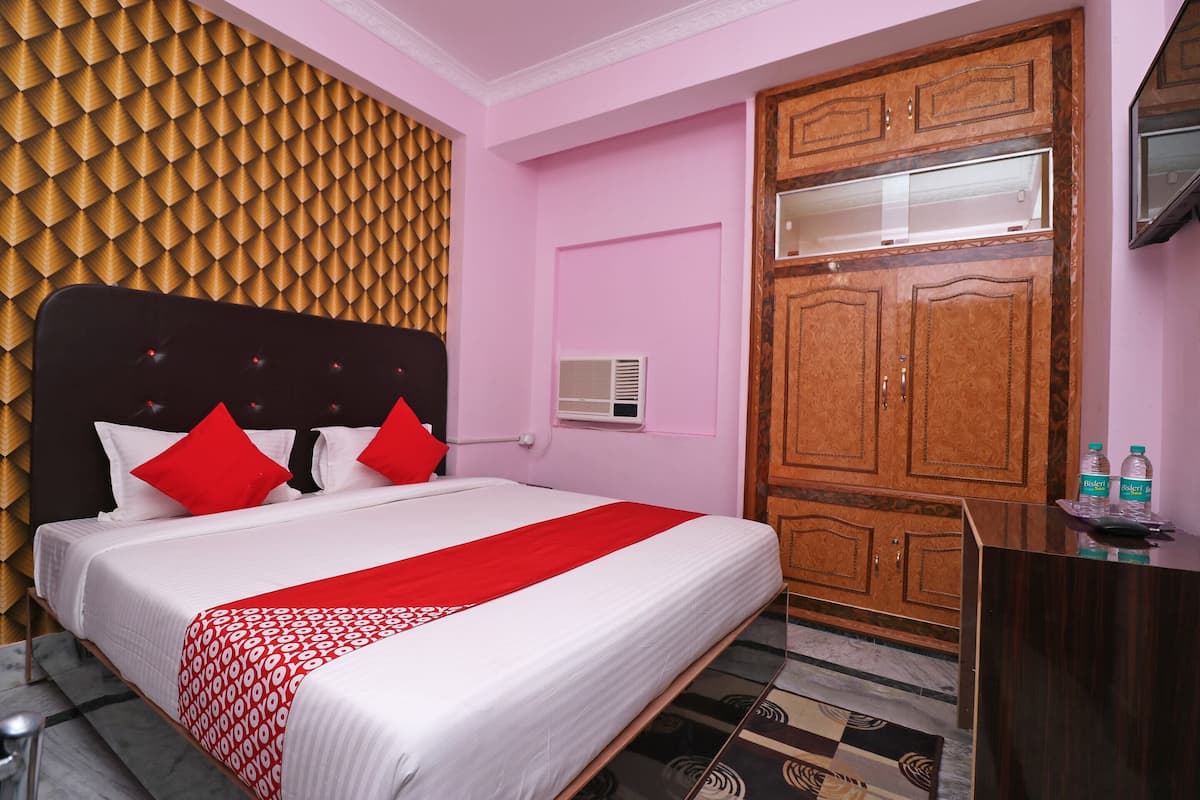 Une chambre d’hôtel équipée d’un lit, d’une armoire en bois, d’un bureau et d’un climatiseur fixé au mur.