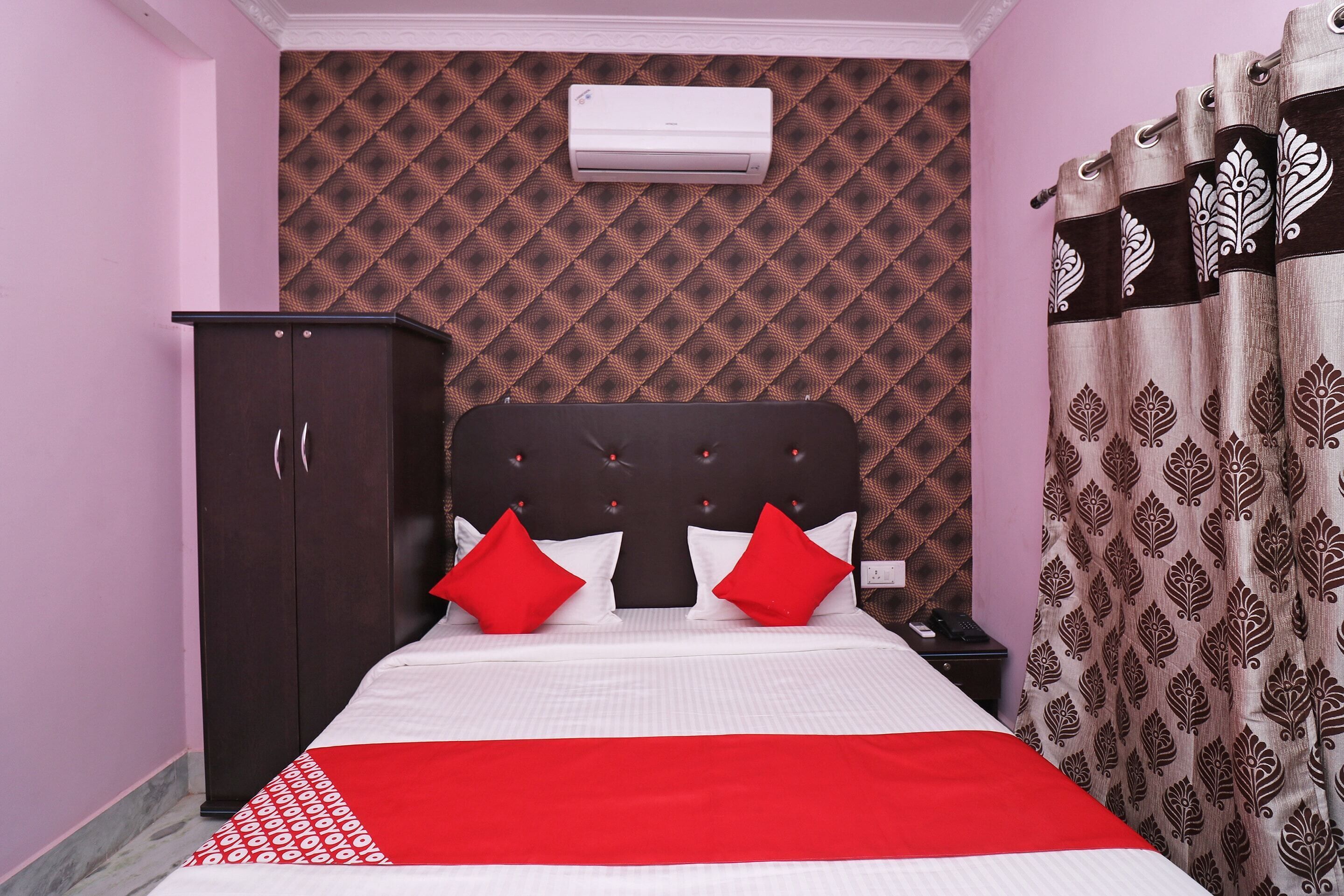 Une chambre à coucher comprenant un lit, une armoire, un climatiseur et des rideaux à motifs.