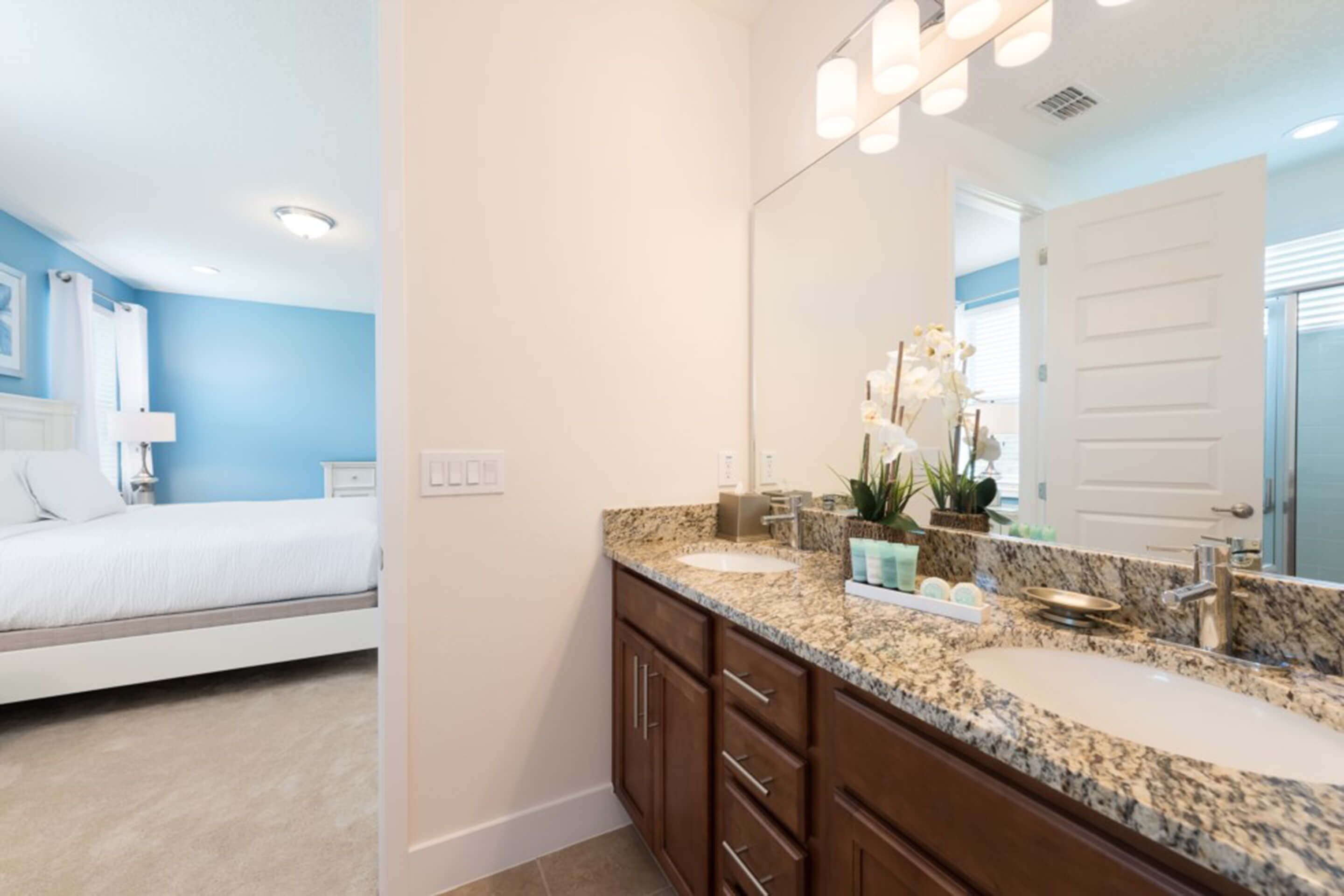 A modern bathroom with a double sink, granite countertop, and a large mirror.