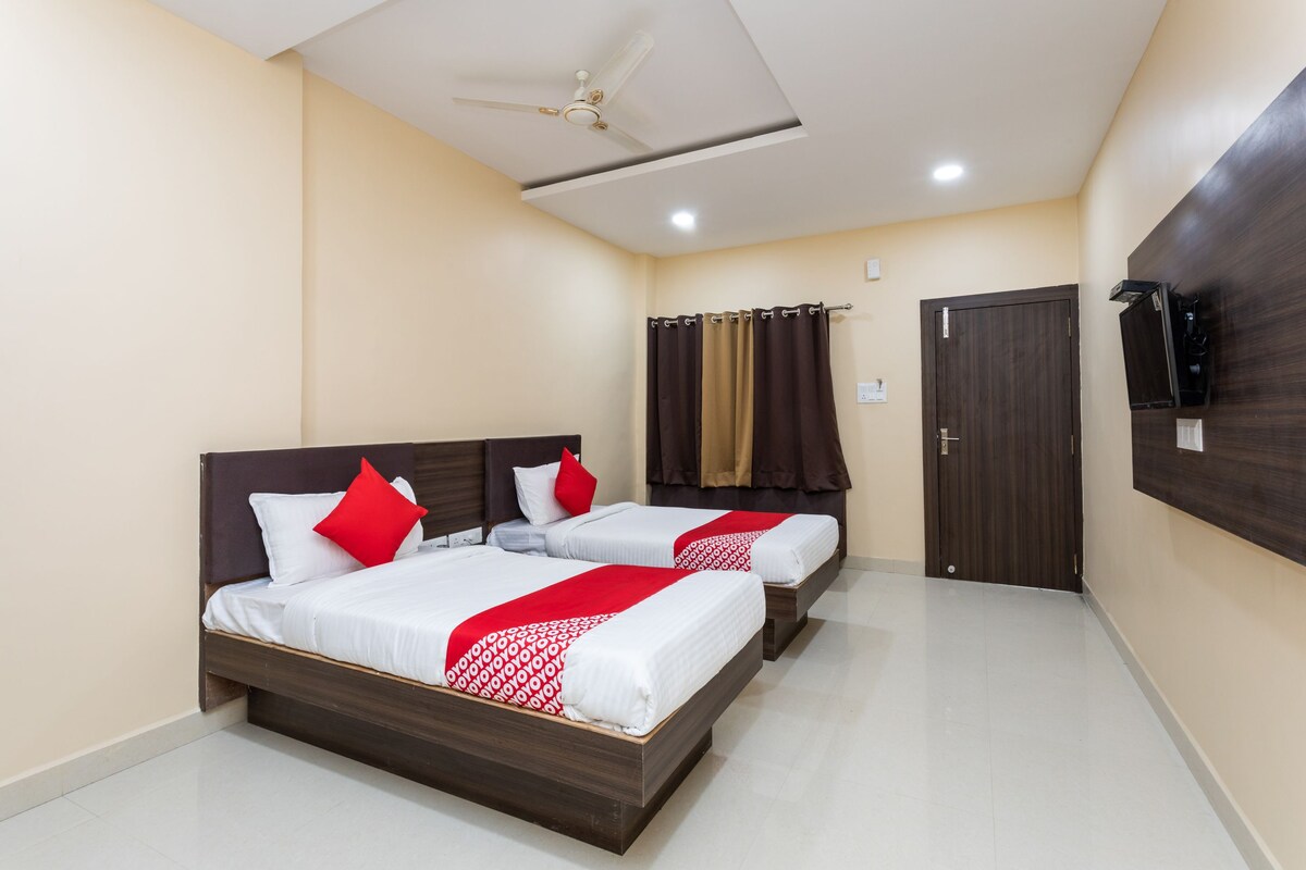 A hotel room with two beds, a ceiling fan, a door, and a mounted TV.