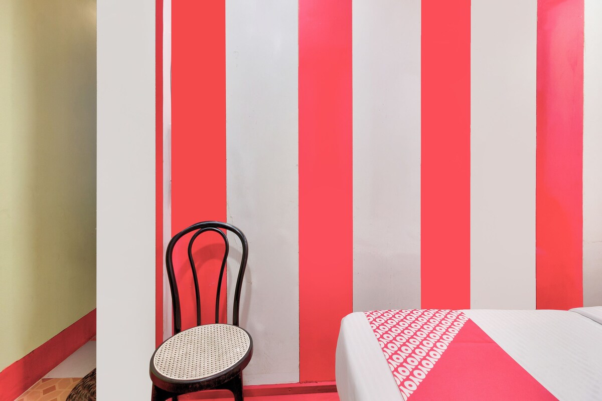 A room with a bed, a chair, and a wall with vertical stripes.
