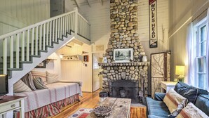 Un interior acogedor con chimenea de piedra, una escalera, un sofá y un comedor.