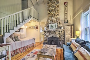 A cozy living room with a stone fireplace, a staircase, and a comfortable seating area. - Saranac Lake Cabin w/ Beach Access (Saranac Lake)
