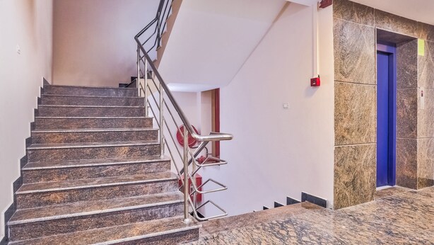 A staircase with metal railings and a marble floor leading to a blue door. - OYO 29878 Sri Abirami Inn (Puducherry)