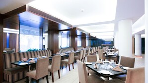 Un restaurant moderne avec des tables hautes et des banquettes, de grandes fenêtres et un intérieur lumineux.