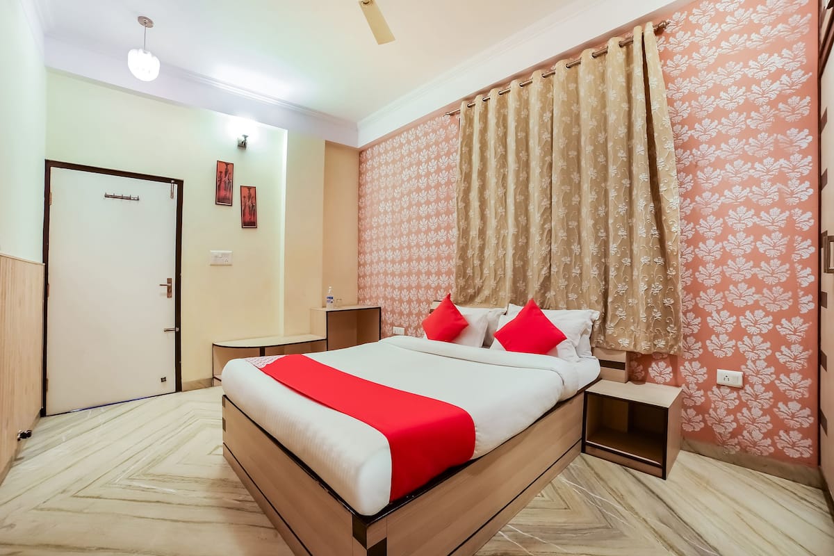 A hotel room with a bed, nightstands, a wardrobe, and a door.