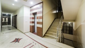 Un pasillo de hotel con piso de mármol, una escalera y una pared con diseño a rayas.