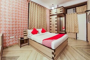 A bedroom with a bed, nightstand, wardrobe, and a mirror. - Capital O 37274 The Royal Palace (Jaipur)
