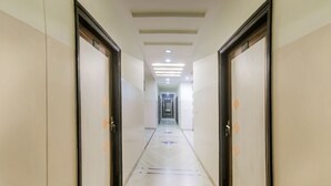 Un pasillo con puertas numeradas 208 y 209, que conduce a una zona central con suelo de baldosas e iluminación empotrada.