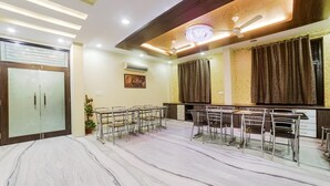 Amplia habitación con piso de mármol, comedor con sillas metálicas, ventilador de techo y candelabro.