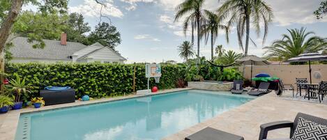 A swimming pool with lounge chairs and a basketball hoop.