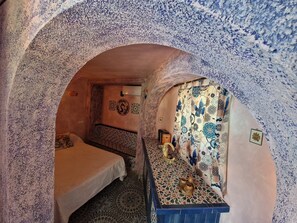 A room with a bed, a small table with a decorative item, and a patterned wall. - pretty house with wonderful sea view wifi available throughout the property (Spagna)
