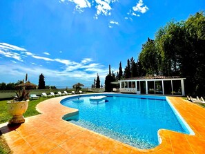 A swimming pool with a curved edge, surrounded by a tiled deck, and a covered area with a glass enclosure. - pretty house with wonderful sea view wifi available throughout the property (Spagna)