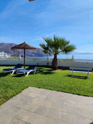 A patio with lounge chairs, a palm tree, and a view of the sea and mountains. - pretty house with wonderful sea view wifi available throughout the property (Spagna)