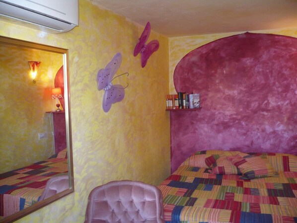 Ein Schlafzimmer mit Bett, Stuhl, Spiegel und Schmetterlingsdekoration an der Wand.