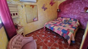 A bedroom with a bed, a chair, a dresser, a mirror, and an air conditioning unit. - pretty house with wonderful sea view wifi available throughout the property (Spagna)