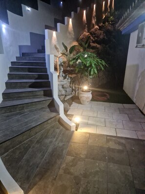 Un escalier avec une rampe blanche, une plante en pot et un mur de pierre.