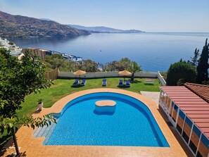 A swimming pool with a curved design, surrounded by a grassy area and lounge chairs. - pretty house with wonderful sea view wifi available throughout the property (Spagna)
