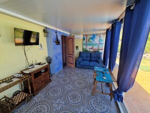 Una sala de estar con televisor, sofá, mesa de centro y suelo estampado.