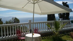 A patio with a white umbrella, red chairs, and a table with a floral tablecloth. - pretty house with wonderful sea view wifi available throughout the property (Spagna)