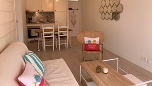 A cozy living room with a sofa, a dining table, and a kitchen in the background. - renovated beach apartment  (Playa de las Americas - Arona)