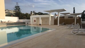 A swimming pool with lounge chairs and a covered seating area. - renovated beach apartment  (Playa de las Americas - Arona)