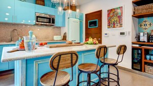 A kitchen with blue cabinets, a white refrigerator, and a wooden island with bar stools. - Villa Amalfi (Tulum)