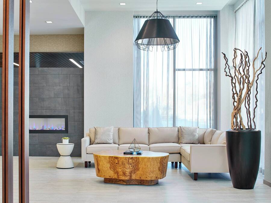 A modern living room with a sectional sofa, a round coffee table, a fireplace, and a large window with curtains.