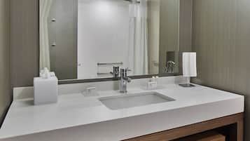 Un baño moderno con un espejo grande, un lavabo y una zona de ducha.