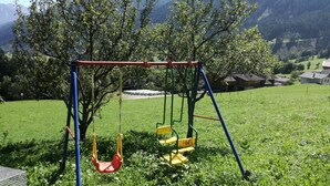 A swing set in a grassy area with a mountain backdrop. - FeWo Mooslechnerhof in a beautiful quiet location (Virgen)