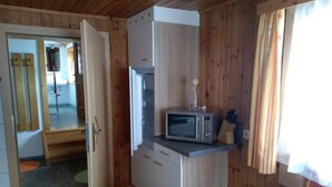 A compact kitchen with a microwave, refrigerator, and wooden cabinets. - FeWo Mooslechnerhof in a beautiful quiet location (Virgen)