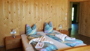A wooden-paneled room with a bed, pillows, and a nightstand. - FeWo Mooslechnerhof in a beautiful quiet location (Virgen)