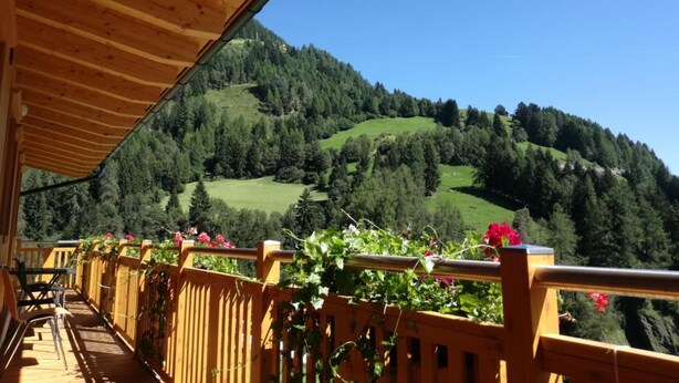 A wooden deck with a view of a forested hillside. - FeWo Mooslechnerhof in a beautiful quiet location (Virgen)
