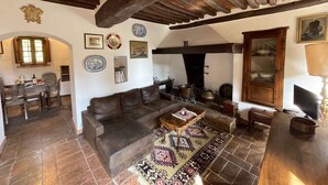 A rustic living room with a stone fireplace, wooden beams, and traditional decor. - Holiday apartment with outdoor pool and WiFi (Cortona)