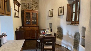 A cozy kitchen with stone walls, wooden cabinets, and a dining table set for two. - Holiday apartment with outdoor pool and WiFi (Cortona)