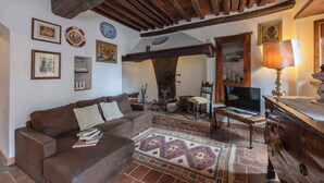 A cozy living room with a brown sofa, a patterned rug, and a television. - Holiday apartment with outdoor pool and WiFi (Cortona)
