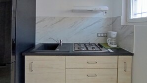 Una cocina compacta con lavamanos, estufa y cafetera.