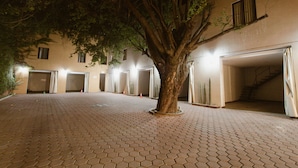 A building with a paved courtyard, a large tree in the center, and multiple garage doors. - Motel Puerta del Cielo (Oaxaca)