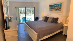 A bedroom with a bed, a desk, a chair, and a painting on the wall. - Contemporary Garden View, Ground Floor Unit, Short Walk to Pool/Beach (Siesta Key)