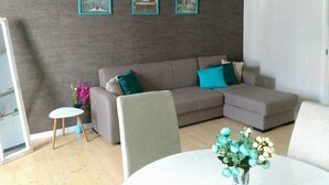 Una sala de estar con un sofá, una mesita y un jarrón decorativo.