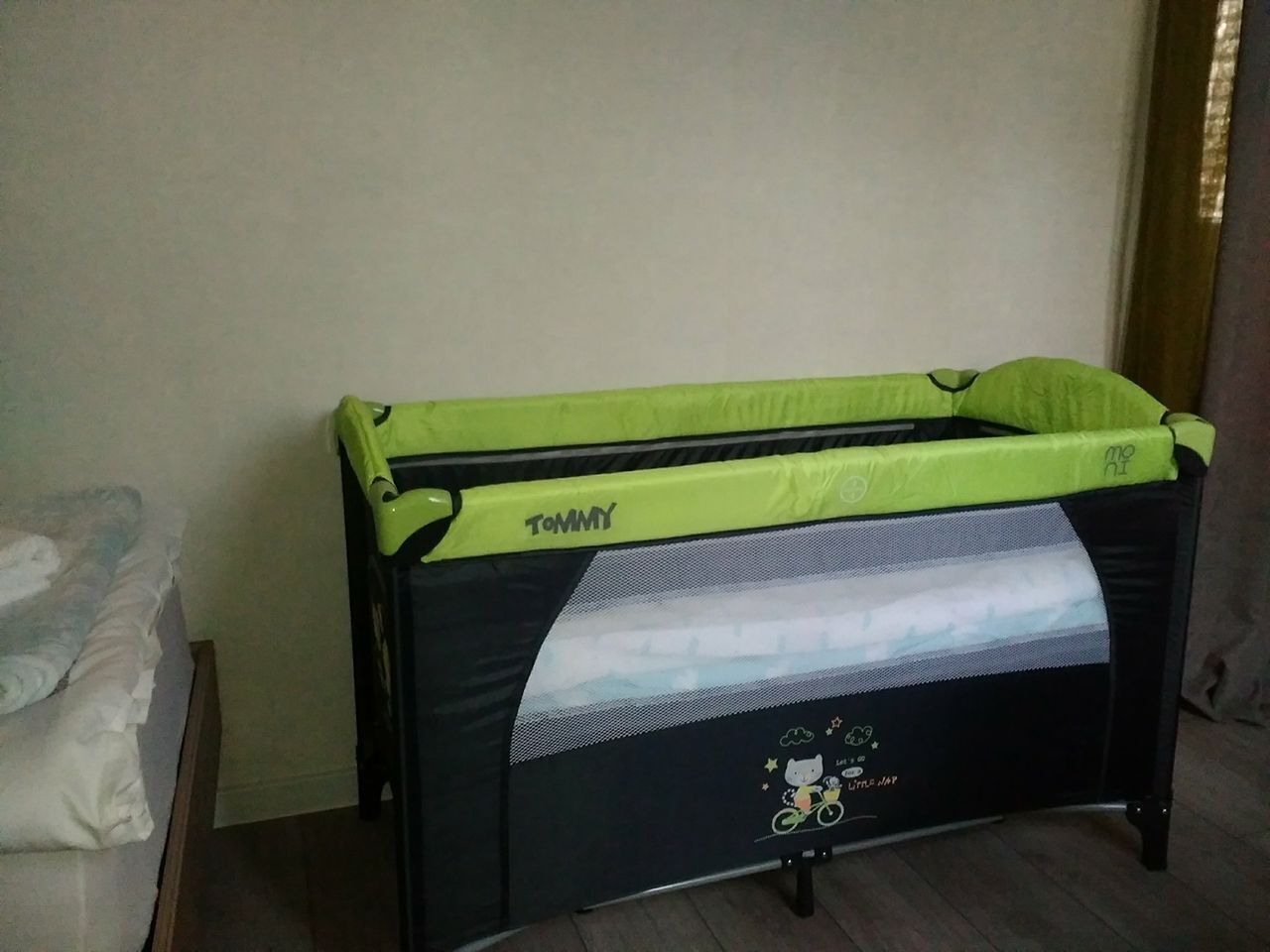 Una cuna negra y verde con dosel de malla, identificada con el nombre 