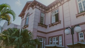 Un edificio rosa con varias ventanas y balcones, rodeado de palmeras.