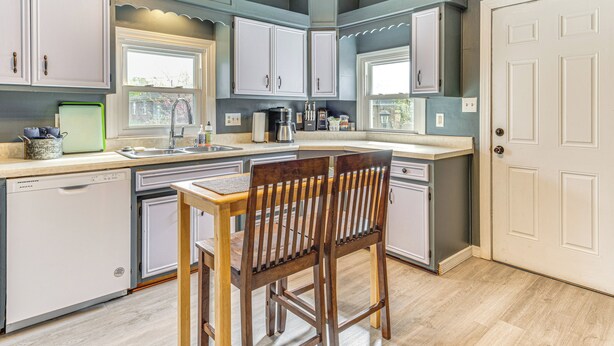 A kitchen with white cabinets, a wooden table, and a white door. - The Junction: Victorian Home in Quaint Fortville! (Fortville)