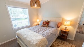 Una camera da letto con un letto, due comodini con lampade, una finestra e un tappeto decorato.