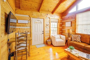 Cozy cabin-style accommodation with a dining table, sofa, and television.