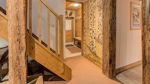 A wooden staircase leading to a second floor, a wooden bench, and a wall with a birch pattern. - Chalet Pele - Alpes Agency - Central Chamonix - Sleeps 11 (Chamonix)