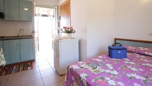 A bedroom with a bed, a dresser, a nightstand, and a window. - Villa Hibiscus - Panoramic studio for 2 people in a villa with pool (Vieste)