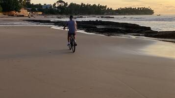 A wide sandy beach with a person riding a bicycle.