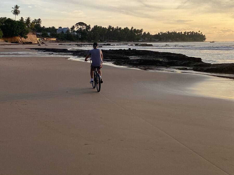A wide sandy beach with a person riding a bicycle.