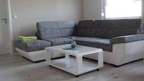 Una sala de estar moderna con un sofá seccional gris, una mesa de centro blanca y un pequeño jarrón decorativo.